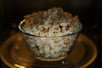 Bowl of tasty popcorn in microwave oven, closeup