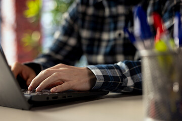 Worker at desk completing spreadsheets on notebook, entering numerical data into cells, calculating...