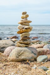This image showcases a carefully balanced stack of smooth, round stones set against a serene beach...