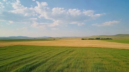 Fototapeta premium Vibrant landscape featuring agricultural fields, hills, and a sky with scattered clouds