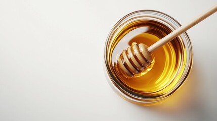 Close-up of golden honey in glass bowl with wooden honey dipper on white background