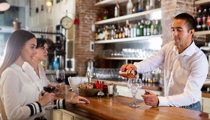 Bartender shaking cocktail for friends, they drinking in nightclub