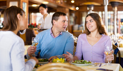 Friendly adult man and young woman, colleagues, having lunch in cozy restaurant ..