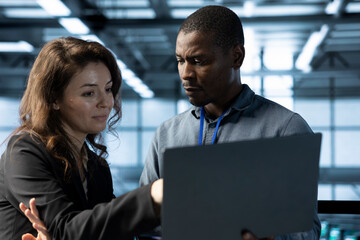 Employees in data center using laptop, integrating green technologies. Server room IT experts doing brainstorming, implementing sustainable energy solutions to maintain environmental standards