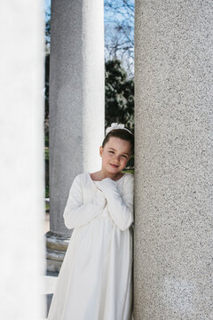 Girl in white dress smiles on First Communion Day