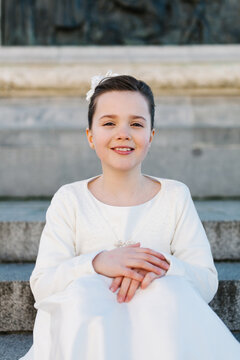 Young girl in white First Communion dress smiling outdoors