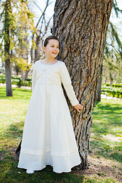 First Communion Day: Girl in White Dress by Tree in Garden