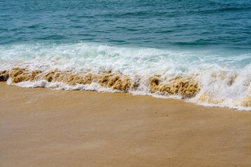 A beautiful sandy beach that features soft golden sand and gentle foamy ocean waves crashing on the shore, creating a serene atmosphere perfect for relaxation and enjoying nature s beauty.