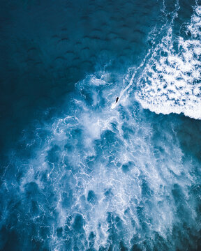 Aerial view of surfer navigating blue waves in Portugal