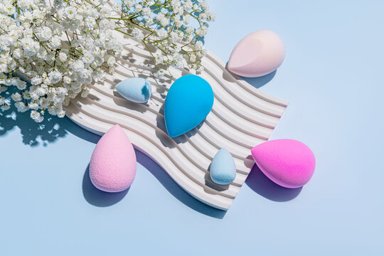 Colorful makeup sponges with flowers on a wavy surface
