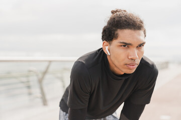 Concentrated serious young african-american mixed-race sportsman male jogger athlete listening to...