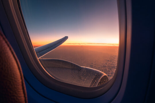 View from airplane window showing wing and sunset