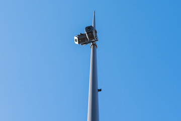 Surveillance cameras on a tall pole against a blue sky