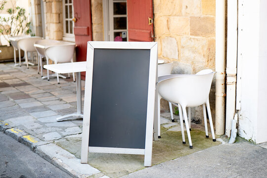 Blank Chalkboard at Outdoor Cafe with White Chairs and Table