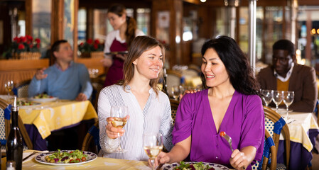 Meeting of two happy girlfriends at dinner in a restaurant