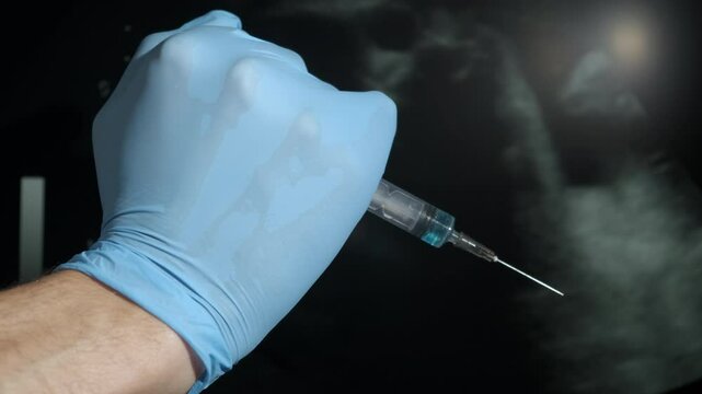 Doctor with abortion syringe. A view of doctor in medical gloves hold an injection by the ultrasound picture with embryo. A concept of abortion problems, and woman body healthcare.