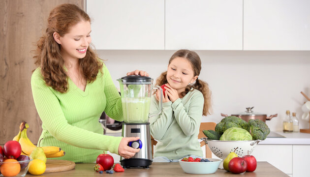 Mother and little daughter making healthy smoothie in kitchen