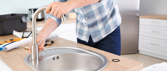 Plumber installing sink in kitchen