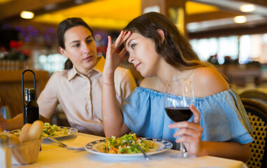 Two best friends have fun talking at a table in a restaurant