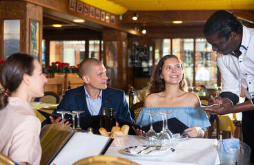 Group of young adult friends looking in menu making order at restaurant