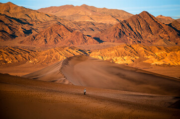 Silhouette of man enjoying the sunset with scenic view on Mesquite Flat Sand Dunes, Death Valley National Park, California, USA. Evening walk in Mojave desert with Amargosa Mountain Range in back