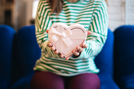 Woman holding heart-shaped gift, sitting in a cafe