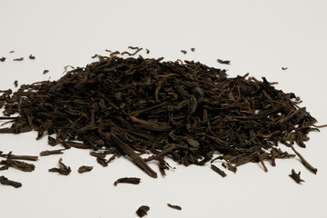 High-quality loose-leaf black tea spread on white surface. Rich, dark leaves ideal for brewing a...