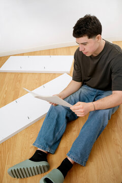 Man reading instructions while assembling furniture