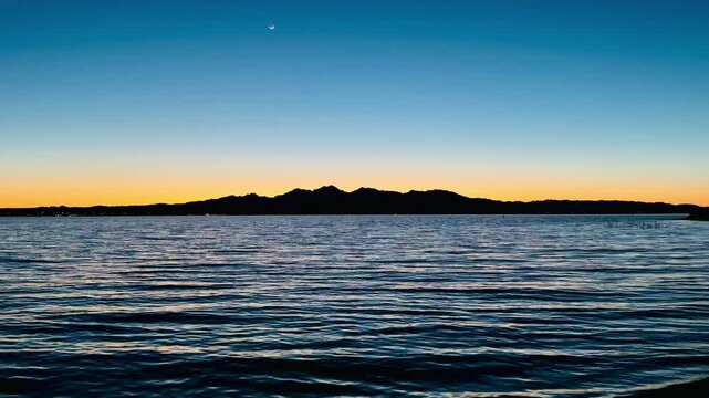 Breathtaking sunset paints the sky in vibrant hues over Lake Havasu, casting a golden glow across the tranquil waters as the California shoreline silhouettes against the horizon.