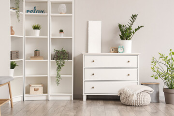 Chest of drawers and pouf with soft blanket in interior of light living room