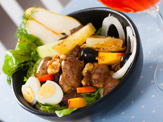 Salad with roasted chicken hearts, fresh greens, fried cheese, quail eggs, ripe pear and peach served with glass of wine
