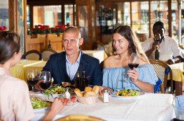 Cheerful friends dining and drinking wine at restaurant