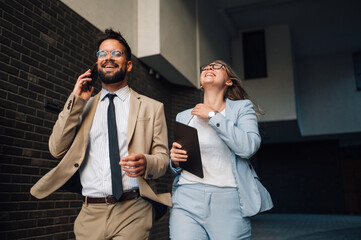 Business partners having phone conversation walking outside office building