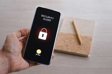Hand holding smartphone displaying security alert with lock icon