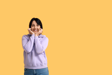 Portrait of happy young brunette on yellow background
