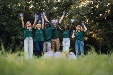Group of volunteers raising their arms after cleaning in the park