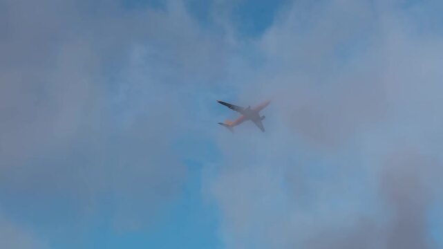 Passenger plane is flying through a cloudy sunset sky. The sky is mostly blue with some clouds scattered throughout. Plane flying low to the ground during landing
