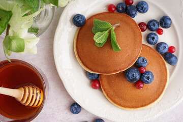 Plate with tasty pancakes and berries on white table