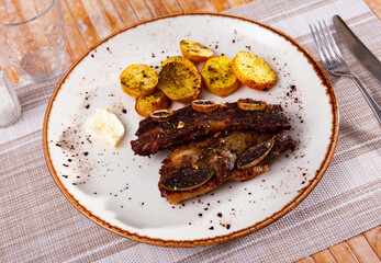 Portion of just cooked churrasco, beef rib steak with grilled potatoes.