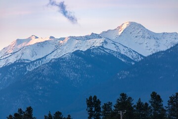 Snowy mountain peaks at dawn, soft light highlighting the frosted peaks. Majestic winter landscape....