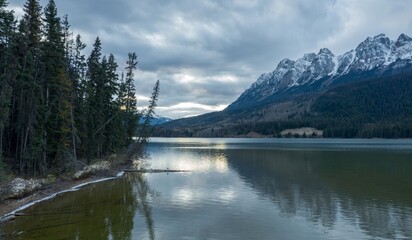 Fototapeta premium Peaceful mountain Yellowhead Lake at twilight. Snow-capped peaks reflect on the still water. Tranquil scenery. Jasper National Park, British Columbia, Canada