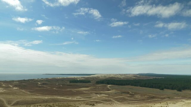 view of Nida dunes, vast sandy terrain with sparse vegetation under blue sky