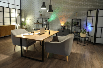 Interior of dark studio with podcaster's workplace, shelf units and glowing lamps