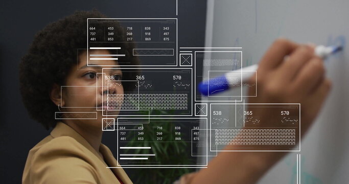 Image of diagrams and data processing over biracial woman taking notes in office