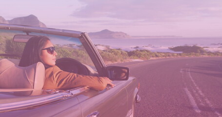 Image of light shade over biracial couple driving car at seaside