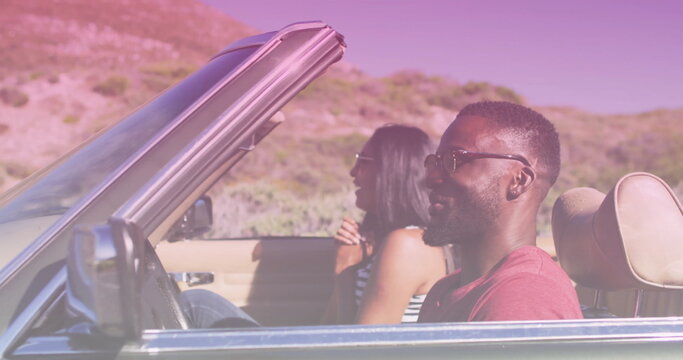 Image of light shade over biracial couple driving car at seaside