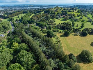 Obraz premium High-angle view of Auckland park, New Zealand. Vast parkland, city views, and a monument are visible. Beautiful green spaces. CORNWALL PARK, AUCKLAND, NEW ZEALAND