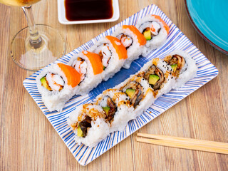 Inside out sushi roll uramaki with unagi, avocado and salmon slices .