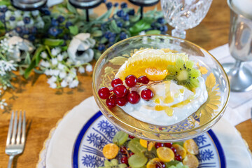 Fruit and Greek Yogurt breakfast with a slice of honey comb and golden berries