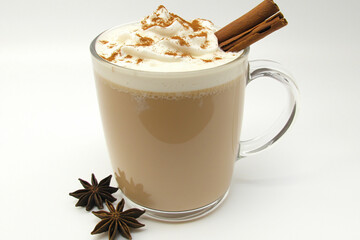 Creamy beverage topped with whipped cream and cinnamon stick, surrounded by star anise on white background